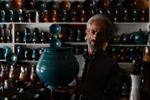 An Afghan potter displays a clay pot inside his shop in Kabul in July 2023. (AFP photo by Wakil Kohsar)